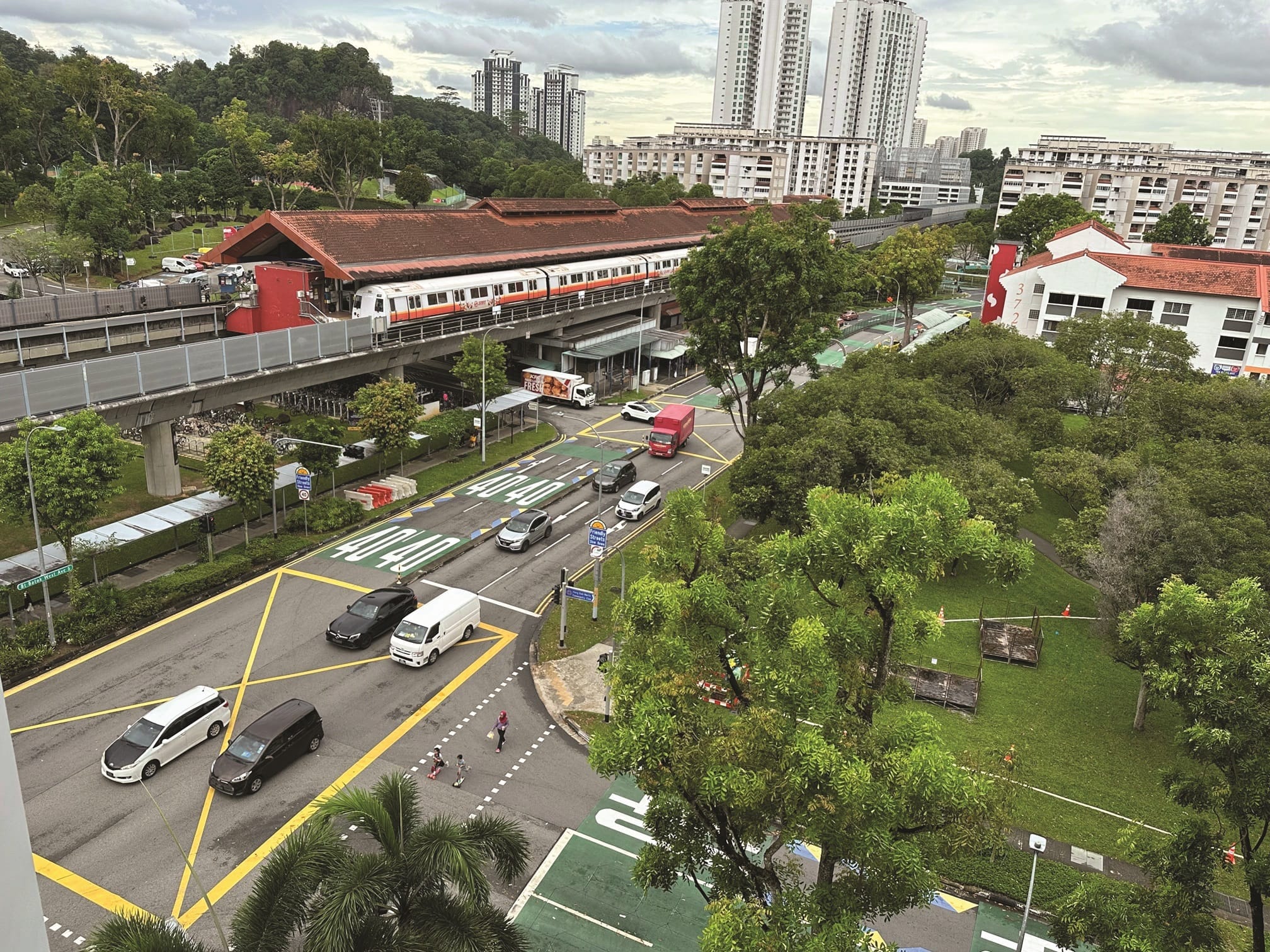 Cityscape view of a train station, a street with cars, and residential buildings.